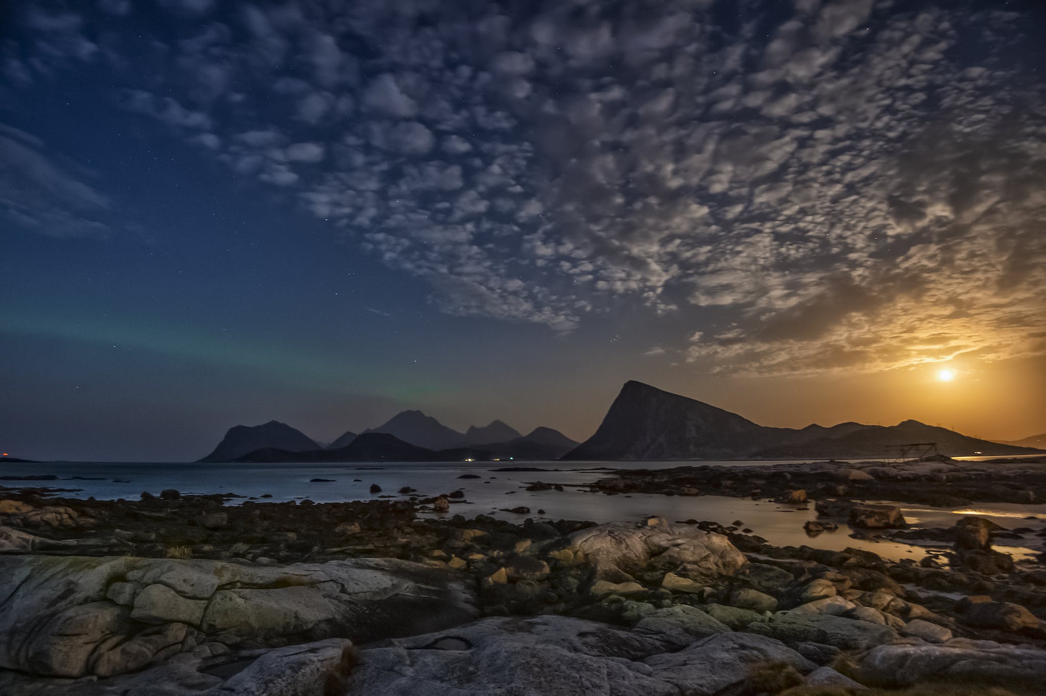 Magnificent landscape of sea waving on rocky coast near mountains in Lofoten archipelago against sunset sky